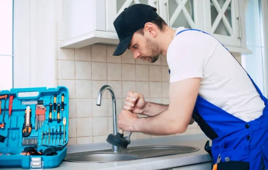 handyman-uniform-is-cleaning-clogged-kitchen-sink-with-help-plunger